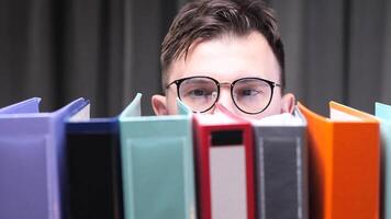 close-up Office worker with glasses searching files in colorful binders archive video