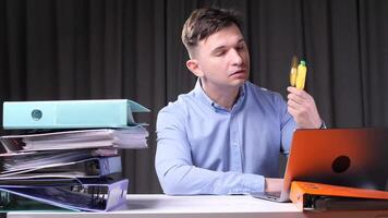 Office worker relaxing with handheld fan while working on laptop video