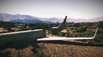 Plane wreckage rests in remote area surrounded by mountains and vegetation video