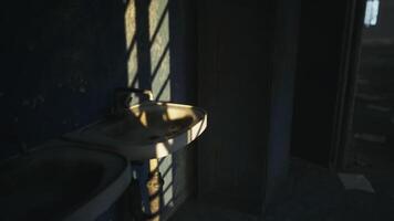 Sunlight streaming through a window onto an old sink in a dimly lit bathroom video