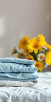 Soft blue sheets stacked neatly with vibrant yellow flowers in the background on a sunny day at home photo