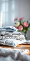 Soft linens arranged neatly on a wooden table beside a vibrant bouquet of flowers in a bright room photo