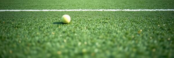 Tennis ball rolls on green artificial turf during a daytime match in a local sports complex photo