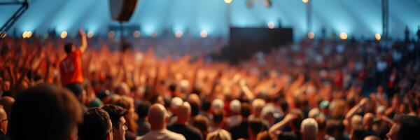 Large crowd celebrates at an outdoor music festival under a tent on a warm summer evening photo