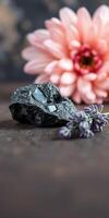 Dark stone crystal with floral background and lavender on wooden surface photo