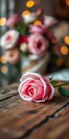 Beautiful pink rose on rustic wooden table with a blurred bouquet in the background and soft lights creating a warm atmosphere photo