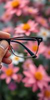 Holding stylish glasses in front of vibrant pink and orange flowers during a bright sunny day on a spring afternoon photo