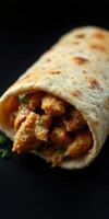 Delicious wrap filled with seasoned chicken and herbs served on a dark background photo