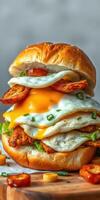 Delicious stacked sandwich with chicken, eggs, and cheese served on a toasted bun photo