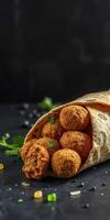 Delicious falafel wrapped in pita with fresh herbs on a dark surface photo