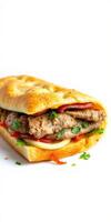 Delicious sandwich with grilled meat, vegetables, and fresh herbs served on a crispy bun photo