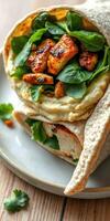 Delicious wrap filled with grilled chicken, fresh greens, and creamy hummus on a rustic plate photo
