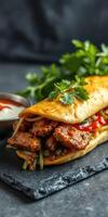 Delicious wrap filled with seasoned meat, vegetables, and sauces served on a dark slate background photo