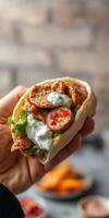 Delicious wrap filled with grilled meat, fresh vegetables, and savory sauce held by a hand photo