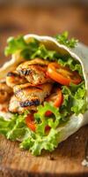 Freshly wrapped grilled chicken wrap with lettuce and tomatoes on a wooden surface photo