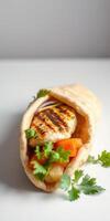 Grilled chicken wrap with fresh vegetables and herbs served in soft pita bread photo