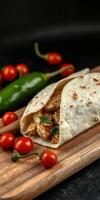 Freshly made chicken wrap with cherry tomatoes and jalapenos on a wooden board photo