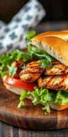 Grilled chicken sandwich with fresh lettuce and tomato on a wooden board in a rustic setting photo