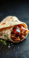 Delicious wrap filled with grilled chicken and vegetables on a dark surface photo