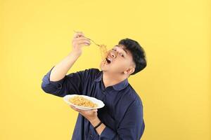 Happy Asian Boy Eating Delicious Mie Goreng on White Plate using Fork. photo