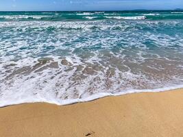 coastal scene with turquoise waves touching sandy beach, distant horizon. High quality photo