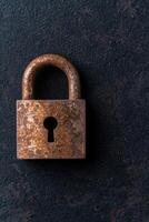 Rusty old padlock on a dark background photo