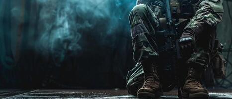 A soldier wearing camouflage uniform and tactical vest is kneeling on the ground in a dark room. photo