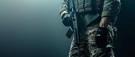 A soldier in full combat gear is standing in a dark room. He is holding a gun and looking to the side. photo