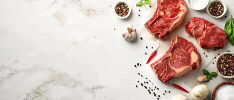 Three pieces of raw beef tenderloin on white marble background with spices and herbs. photo