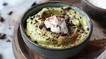 Bowl of creamy sugar-free avocado mousse topped with coconut cream and cocoa nibs, photo