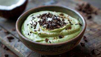 Bowl of creamy sugar-free avocado mousse topped with coconut cream and cocoa nibs, picture photo