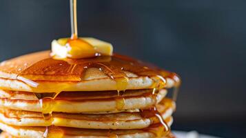A close-up of a stack of golden brown pancakes dripping with maple syrup and topped with a pat of melting butter, photorealistic photo