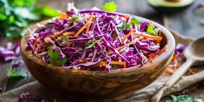 Colorful raw coleslaw with shredded red cabbage, carrots, and creamy avocado dressing in a rustic wooden bowl, photo