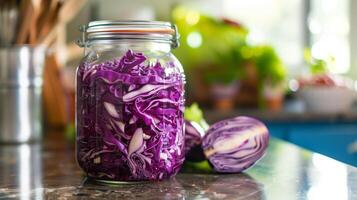A jar filled with shredded red cabbage in brine placed on a kitchen counter for fermentation, photo