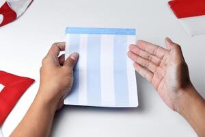 A person holds and opens a savings account book with a red and white background photo