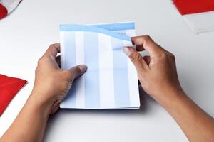 A person holds and opens a savings account book with a red and white background photo