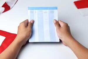 A person holds and opens a savings account book with a red and white background photo