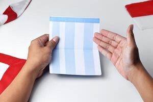 A person holds and opens a savings account book with a red and white background photo