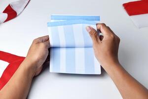 A person holds and opens a savings account book with a red and white background photo