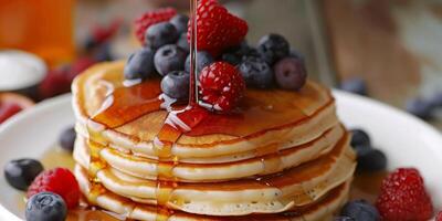 Stack of plant-based pancakes with mixed berries and maple syrup drizzle, photorealistic photo