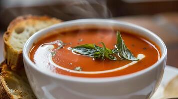 Steaming bowl of tomato basil soup garnished with cream drizzle and fresh basil served with crusty bread, photography photo