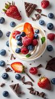 Frozen Yogurt cup filled with blueberries, strawberries, pirouline on top, top-down view, white background, fresh fruits and chocolates surrounding, picture photo
