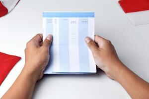 A person holds and opens a savings account book with a red and white background photo