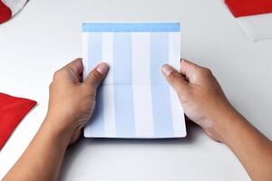 A person holds and opens a savings account book with a red and white background photo