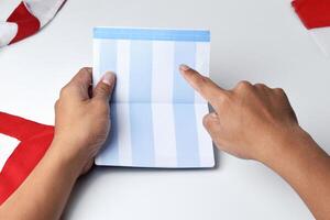 A person holds and opens a savings account book with a red and white background photo
