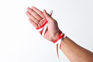 Hands spread with a red and white ribbon photo