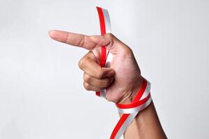 Human hand pointing with index finger with red and white ribbon photo