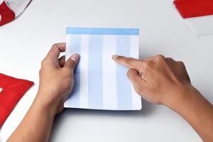 A person holds and opens a savings account book with a red and white background photo