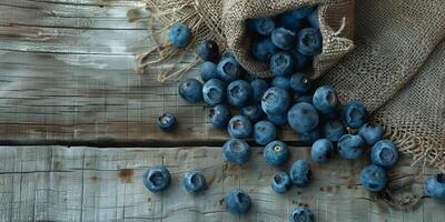 Organic blueberries scattered on a rustic wooden surface with a burlap bag, picture photo