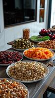 Overhead view of large round table with melon seeds, peanuts, jujubes, raisins, and snacks, near a TV on white wall, photorealistic photo